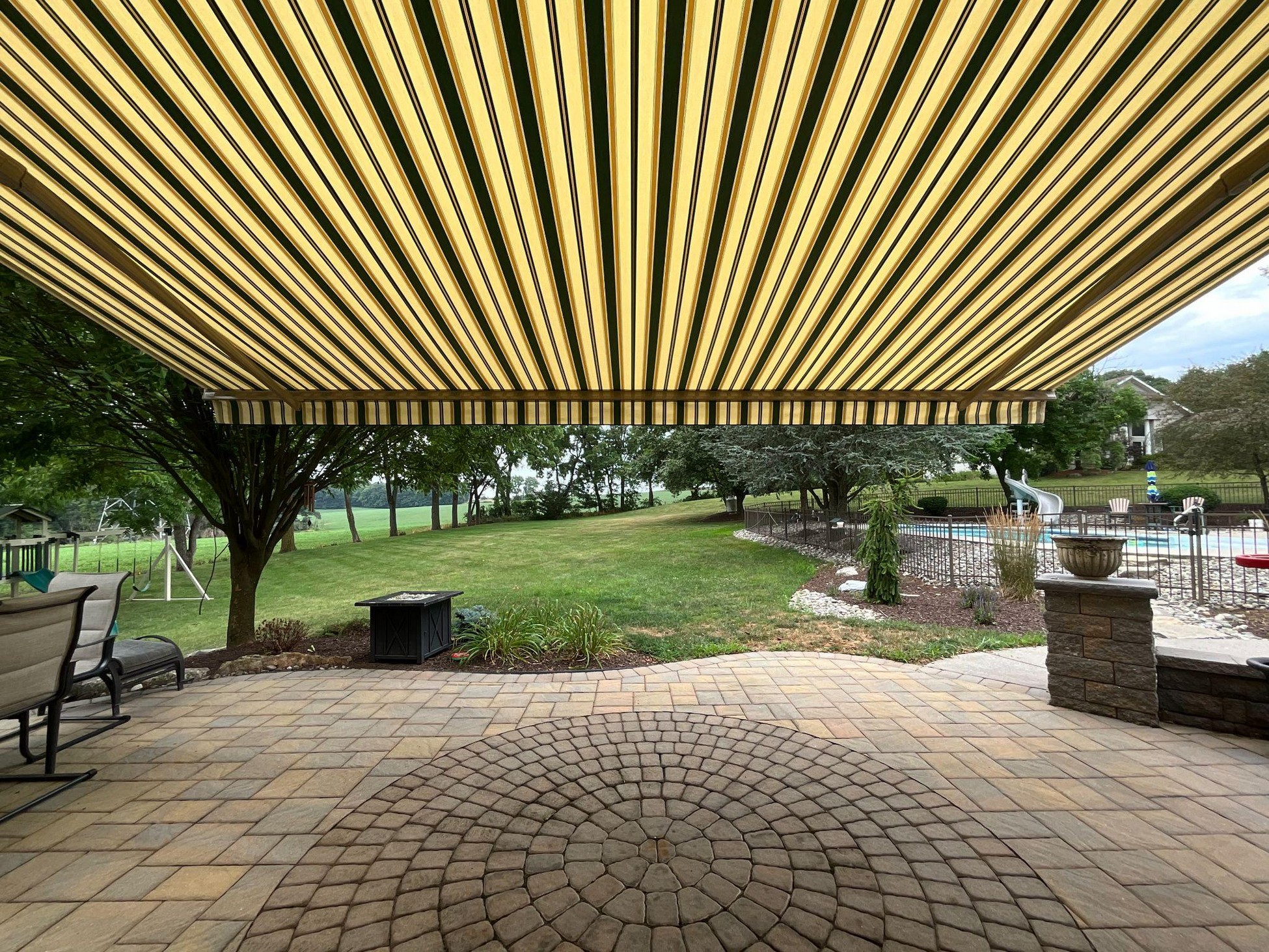 A patio with seats and tables covered by a custom awning